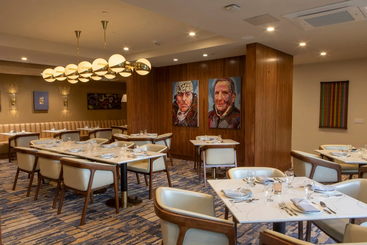 Alice B.’s warm wood-paneled dining room with colorful portraits and set tables.