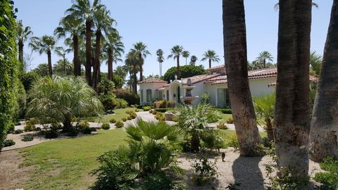 White Spanish Colonial Revival exterior of Casa Adaire behind palms and desert landscaping.
