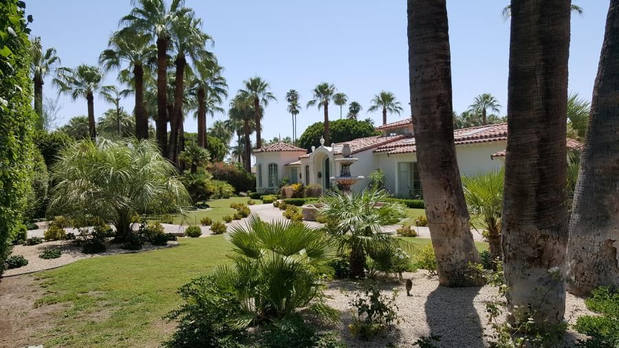 White Spanish Colonial Revival exterior of Casa Adaire behind palms and desert landscaping.