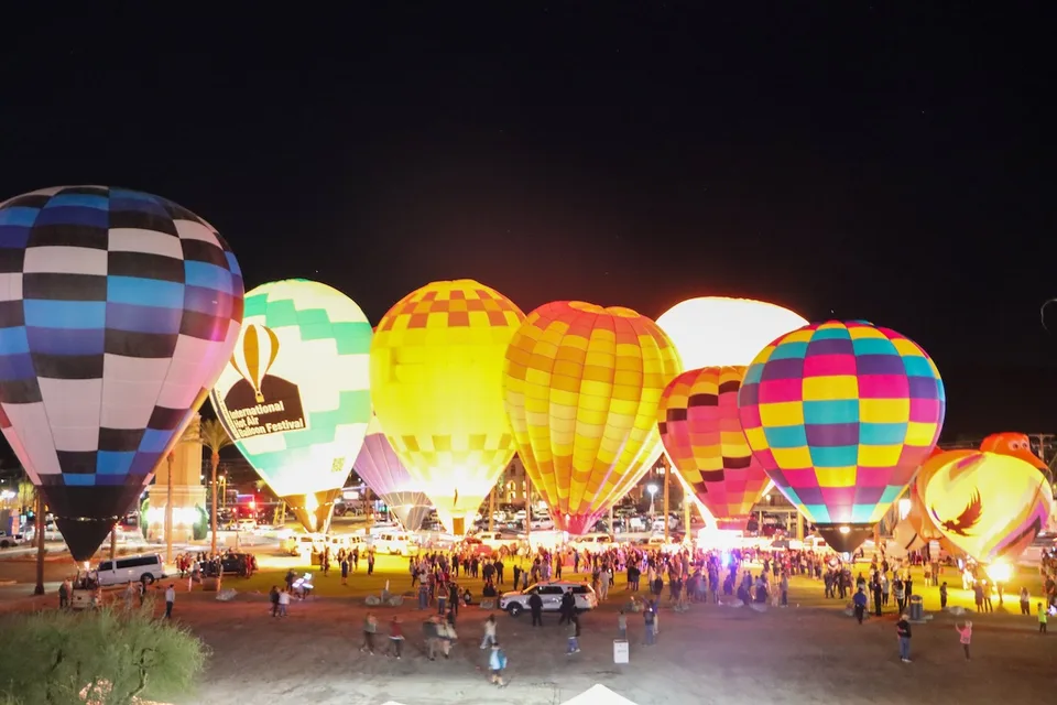 Colorful hot air balloons glow after dark as visitors gather at the Cathedral City festival.