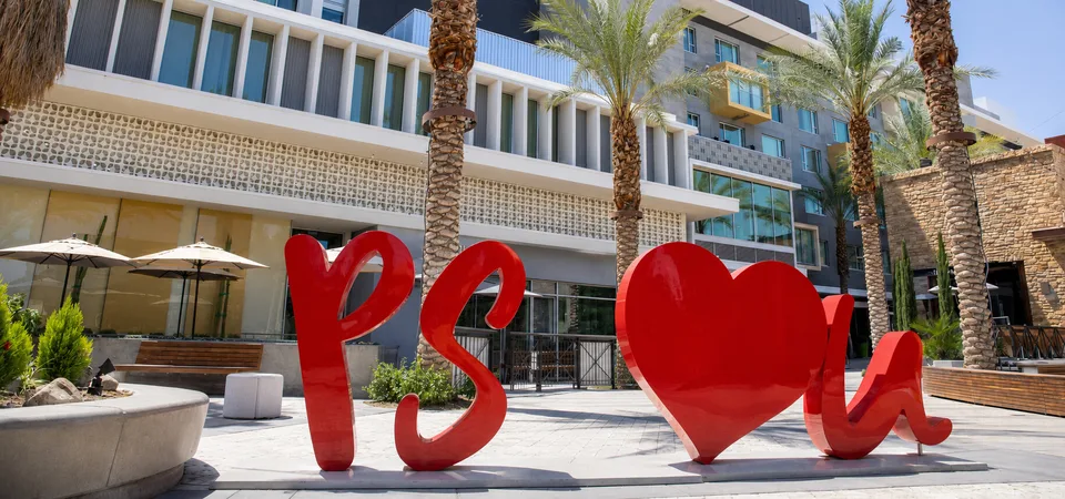 The red PS I Love You sculpture stands in a palm-lined plaza beside the Rowan hotel in downtown Palm Springs.