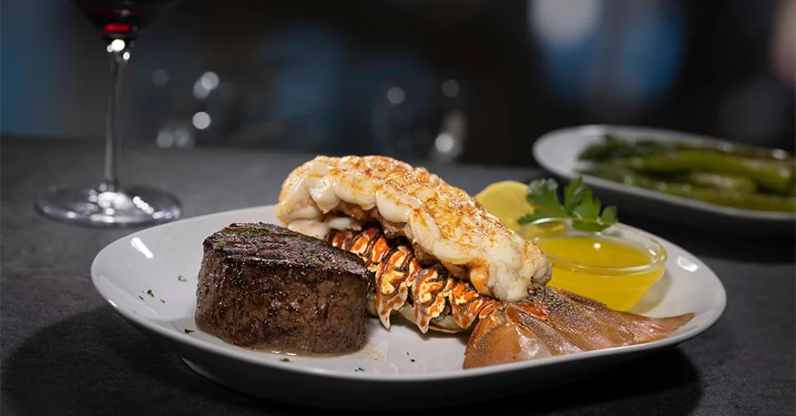 A center-cut filet mignon and lobster tail plated with drawn butter at Eddie V's.