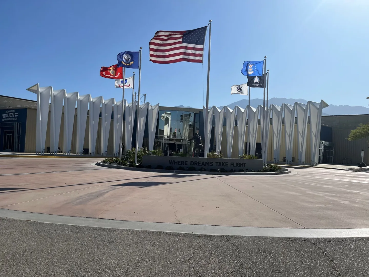 The Palm Springs Air Museum entrance displays flags and aircraft against a clear desert sky.