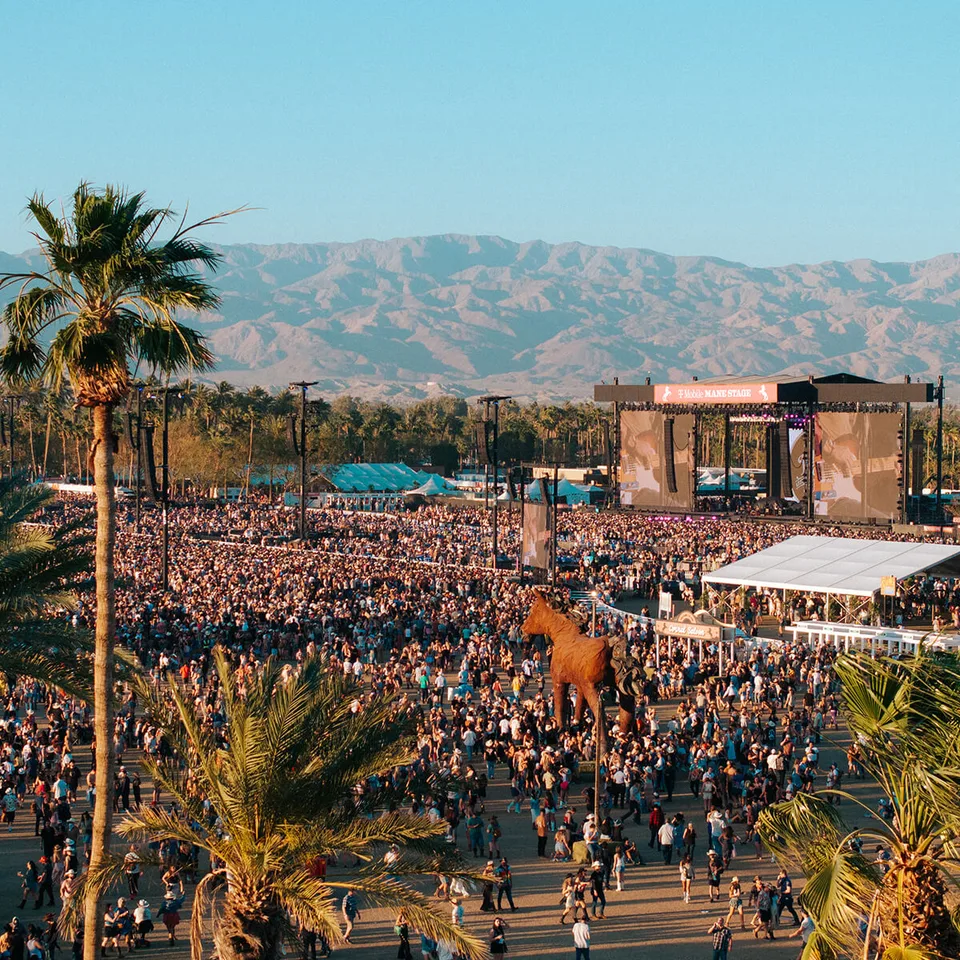 Stagecoach crowds fill the polo fields between palm trees, tents, and a mountain-backed main stage.