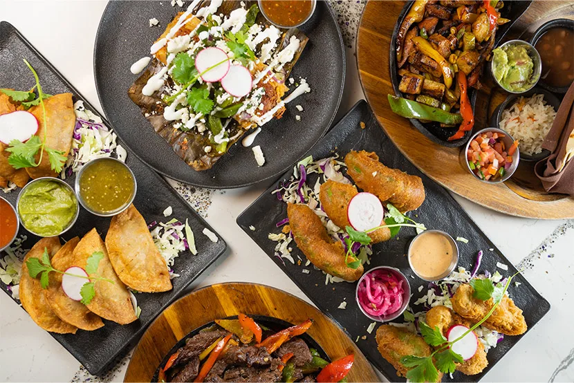 A colorful Tac/Quila spread of tacos, enchiladas, fajitas, and fresh salsas.