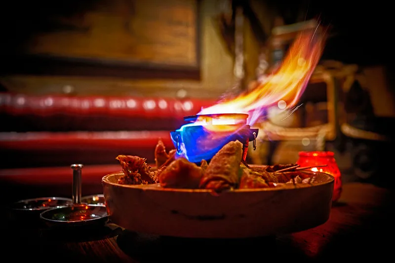 A flaming blue tiki drink rises from a pu pu platter on a table inside Tonga Hut Palm Springs.
